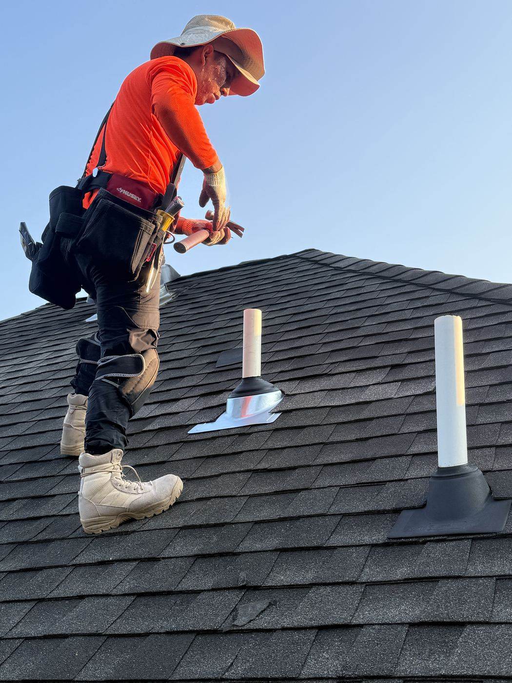 Roofer sealing a pipe boot on architectural shingles